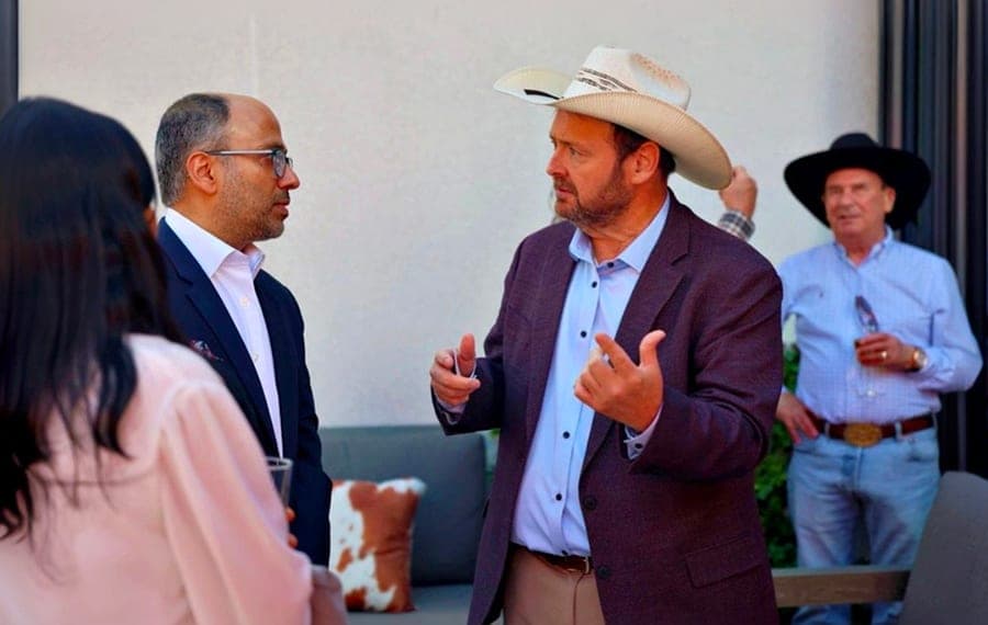 Guests, one in a cowboy hat, discussing business opportunities